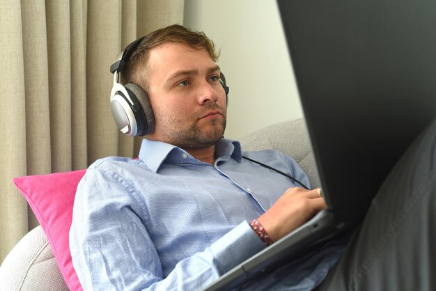 Young man freelancer working from home with his laptop laying on couch