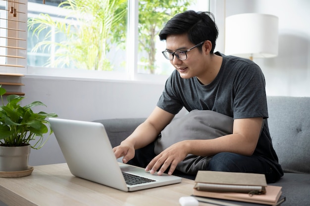 young man freelancer working with computer laptop on sofa at home.