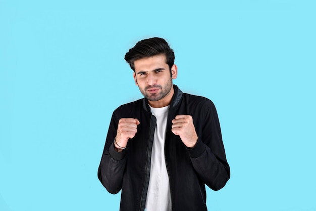 Young man front pose wearing winter clothes feeling cold on blue background indian pakistani model