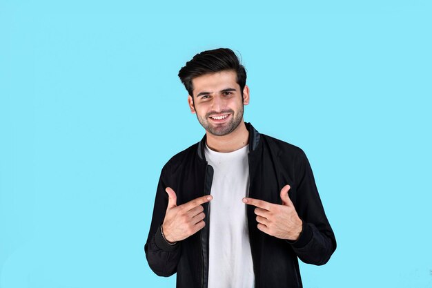 Young man front pose wearing winter clothes feeling happy on blue background indian pakistani model