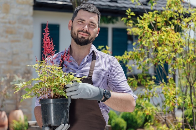 園芸用品センターで手に多年生植物を持つ若い男の庭師