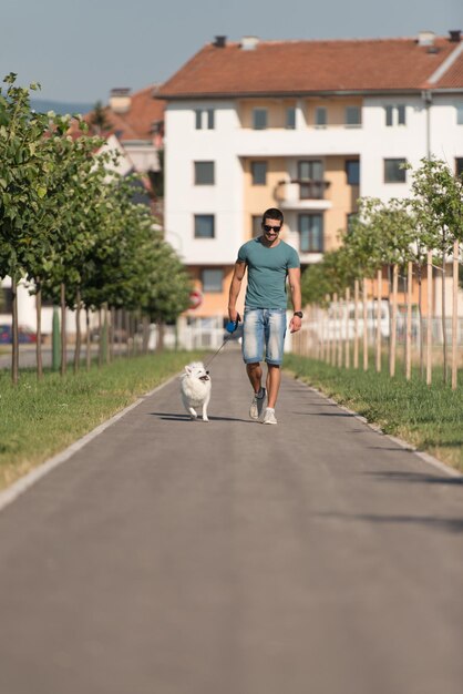 젊은 남자와 독일 스피츠가 공원에서 산책하며 개를 목줄에 매다