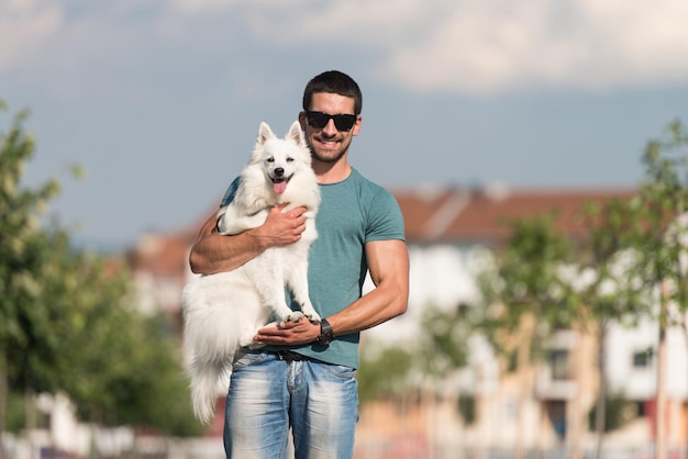 若い男とジャーマン・スピッツが公園を散歩し、犬をひもにつないでいる