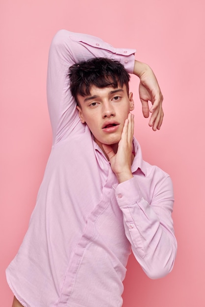 A young man gestures with hands emotions hairstyle fashion pink background unaltered