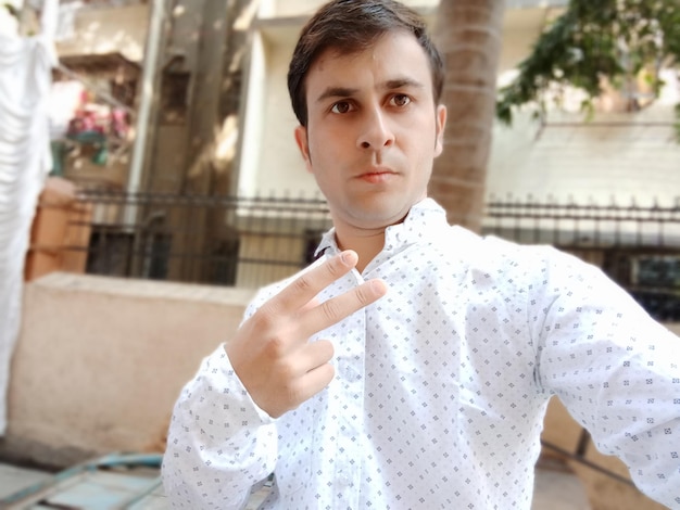 Photo young man gesturing while standing outdoors