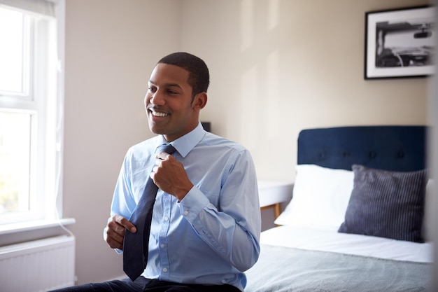 Young Man Getting Dressed In Bedroom For First Day At Work In Office