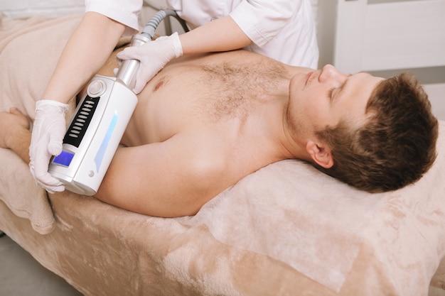 Photo young man getting endospheres massage at beauty clinic