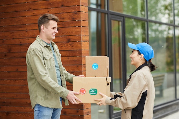 Young man getting his parcels from the courier while they standing outdoors