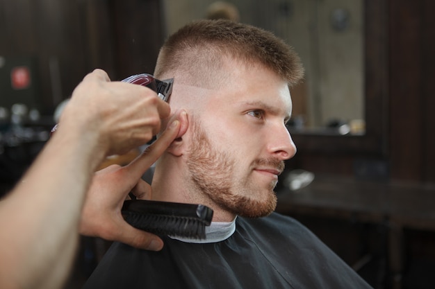 Foto giovane che ottiene nuovo taglio di capelli al negozio di barbiere