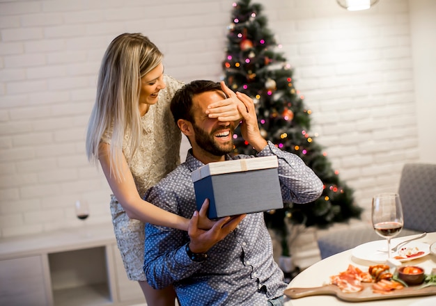 Молодой человек получает подарок от любящей женщины на Рождество или Новый год