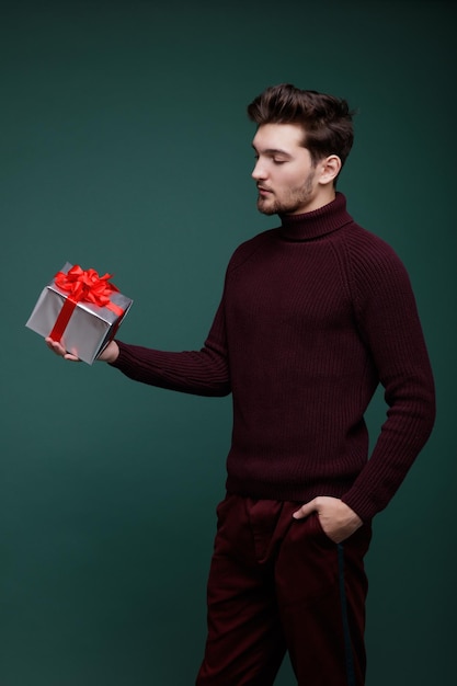 Young man, gifts boxes red silk bows New Year Christmas Fashion photo Studio Shot Green background