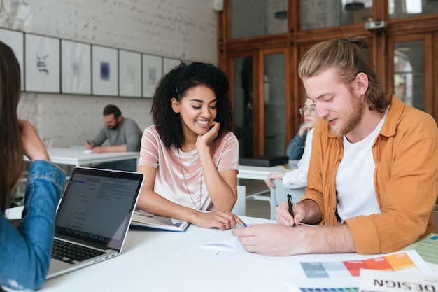 Young man and girl working and making notes together in office