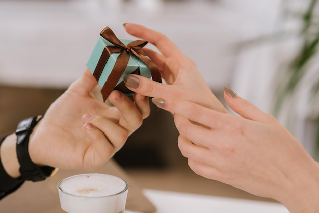 Young man gives a box with present to his girlfrient at the restaurant