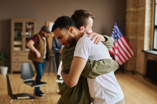 Photo young man giving hug to his friend with post traumatic syndrome