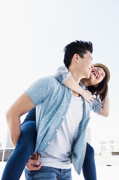 Young man giving a piggyback ride to woman outdoors