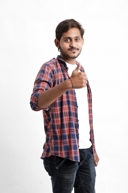 Young man giving thumb up over white wall