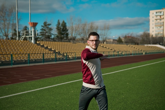 Giovane uomo con gli occhiali che si estende su uno stadio