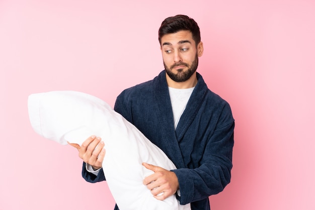 Young man going to sleep on pink wall