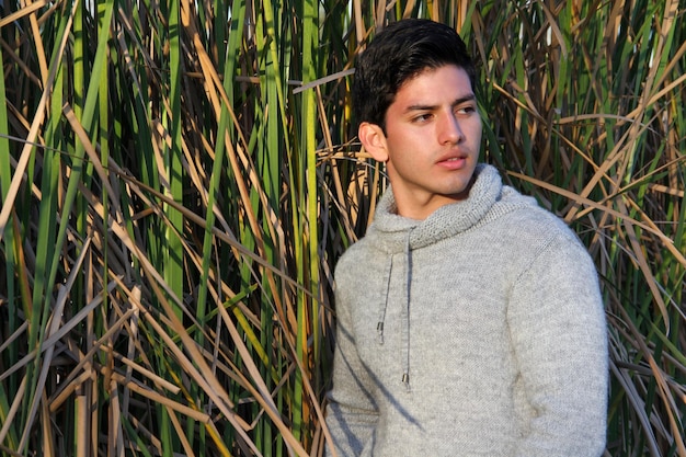 Photo young man in the grass wearing gray sweater