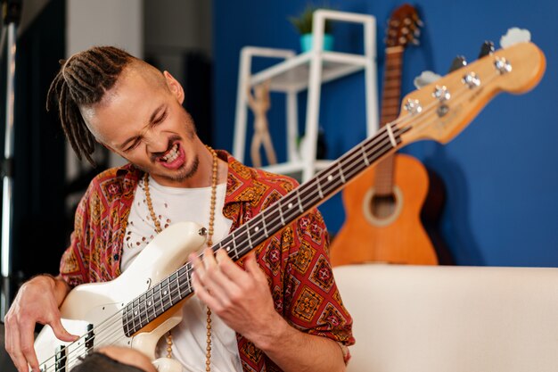 Young man guitar player sitting and performing on a couch