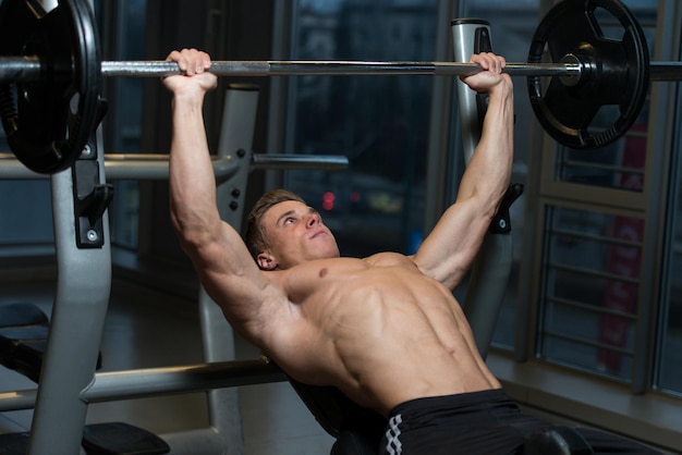 Young Man In Gym Exercising Chest On The Bench Press