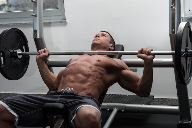 Young Man In Gym Exercising Chest On The Bench Press