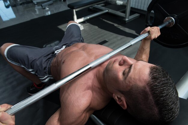 Young Man In Gym Exercising Chest On The Bench Press