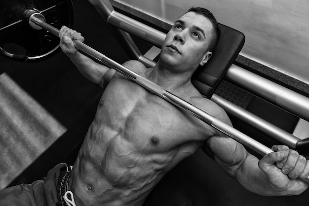 Young Man In Gym Exercising Chest On The Bench Press