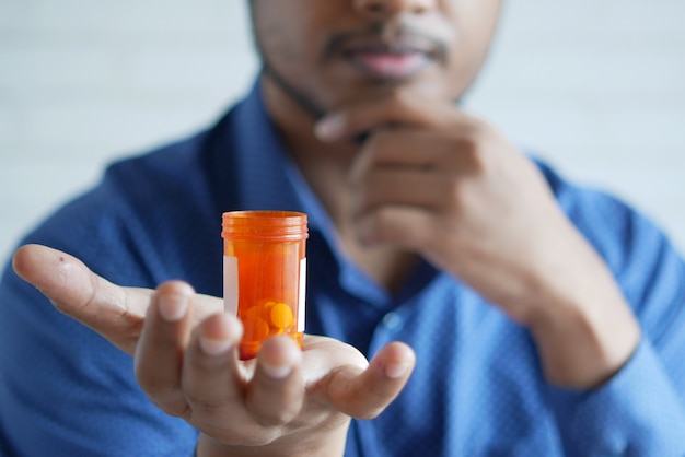 Young man hand holding medicine pill container white sited