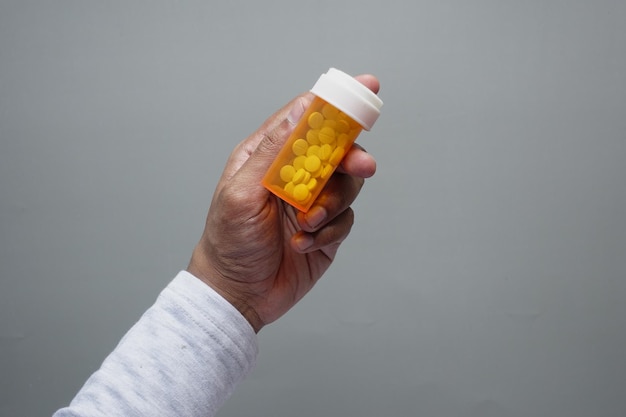 Young man hand holding medicine pill container