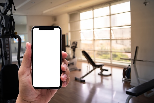 Young man Hand holding smartphone in gym to  fitness phone fitness exercise concept