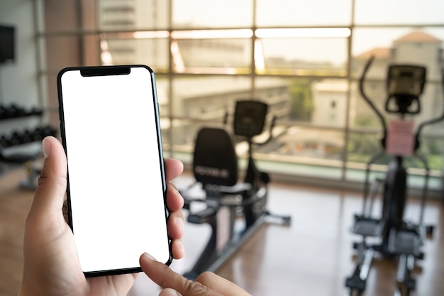 Young man Hand holding smartphone in gym to  fitness phone fitness exercise concept