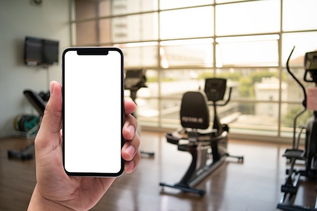 Young man Hand holding smartphone in gym to  fitness phone fitness exercise concept