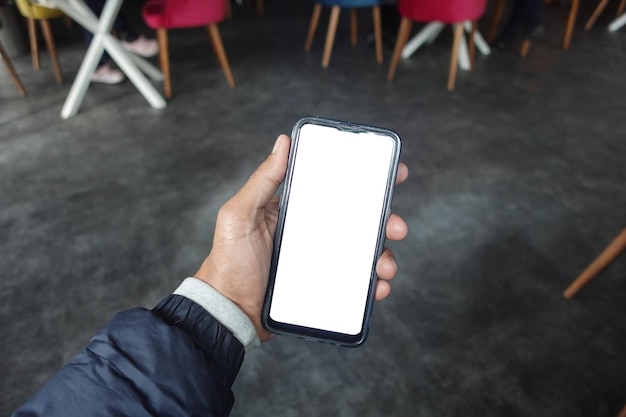 Young man hand using smart phone with green screen at cafe