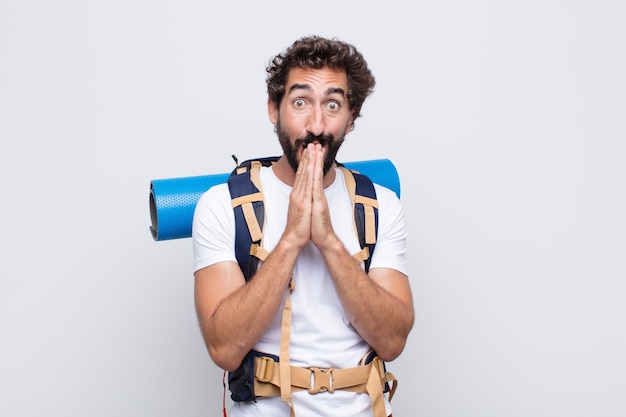 Young man happy and excited, surprised and amazed covering mouth with hands, giggling with a cute expression