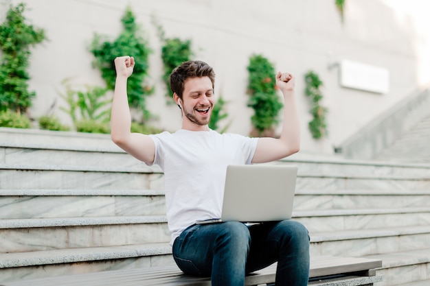 Young man happy with laptop for freelance work outdoors