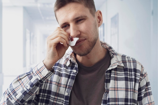 A young man has broken nose with blood going out it and stop it with a napkin unfortinate accident