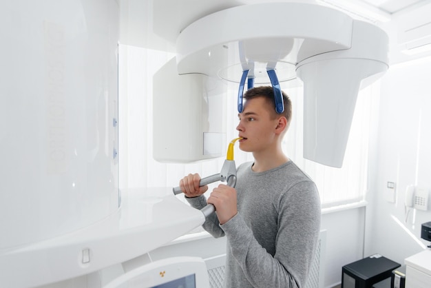 A young man has a computed tomography of the jaw a circular snapshot of the jaw in modern dentistry Prevention of caries prosthetics and dental treatment Radiology panoramic scanner