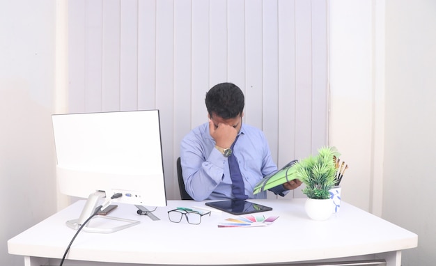 Young man has a headache at work while working on a desktop