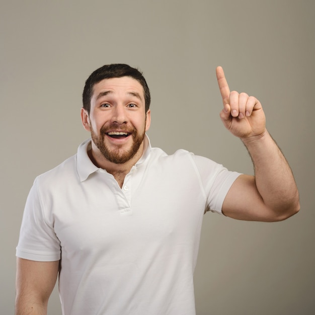 Young man has idea, pointing with finger up isolated on gray background. Smart guy solved a problem. Positive face expression,body language, life perception creativity