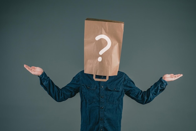 A young man has a paper bag on his head with a question mark, asking why, looking for answers