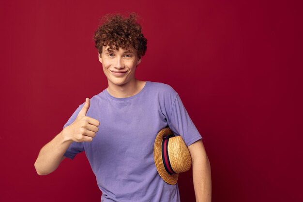 A young man in Hat purple tshirts posing emotions red background unaltered