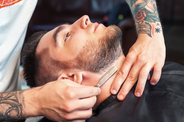 Young man having beard shaven