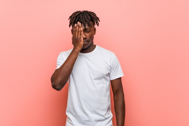 Young man having fun covering half of face with palm.