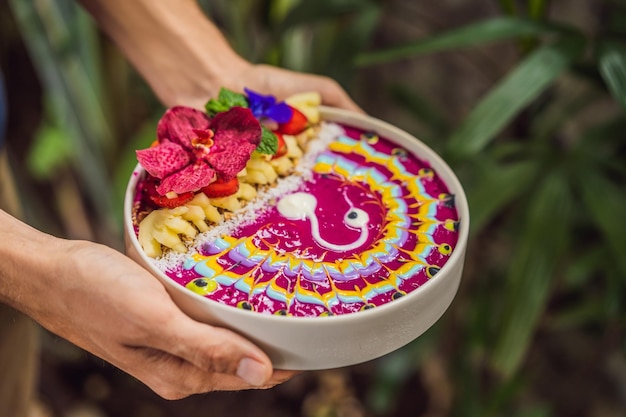 Young man having a mediterranean breakfast eats healthy tropical breakfast smoothie bowl with