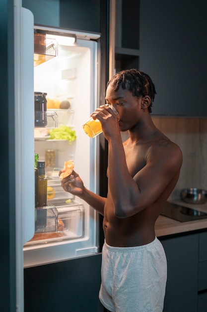 Foto giovane che fa uno spuntino nel cuore della notte a casa accanto al frigorifero