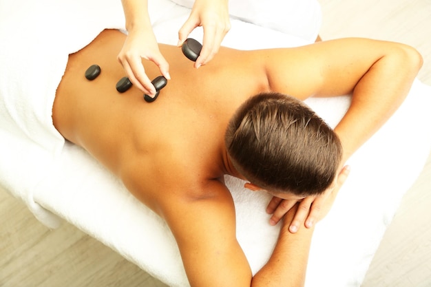 Young man having stone massage in spa salon