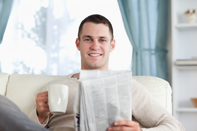 Young man having a tea while reading the news