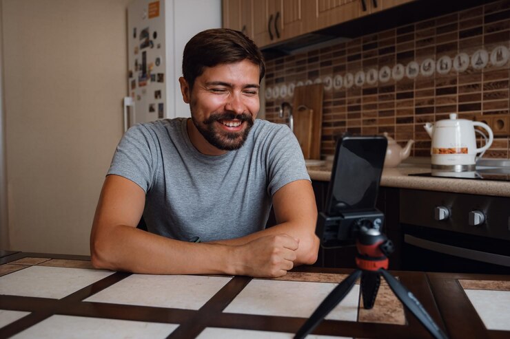 Photo young man having video call via smartphone in the home office