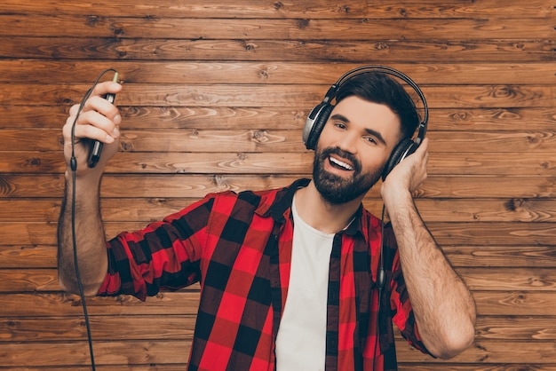 Young man in headphones singing on the of wooden wall